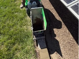 Crew member installing concrete curbing near solar panels