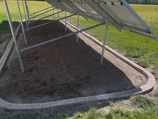 Decorative concrete curbing around shrub bed near outbuilding